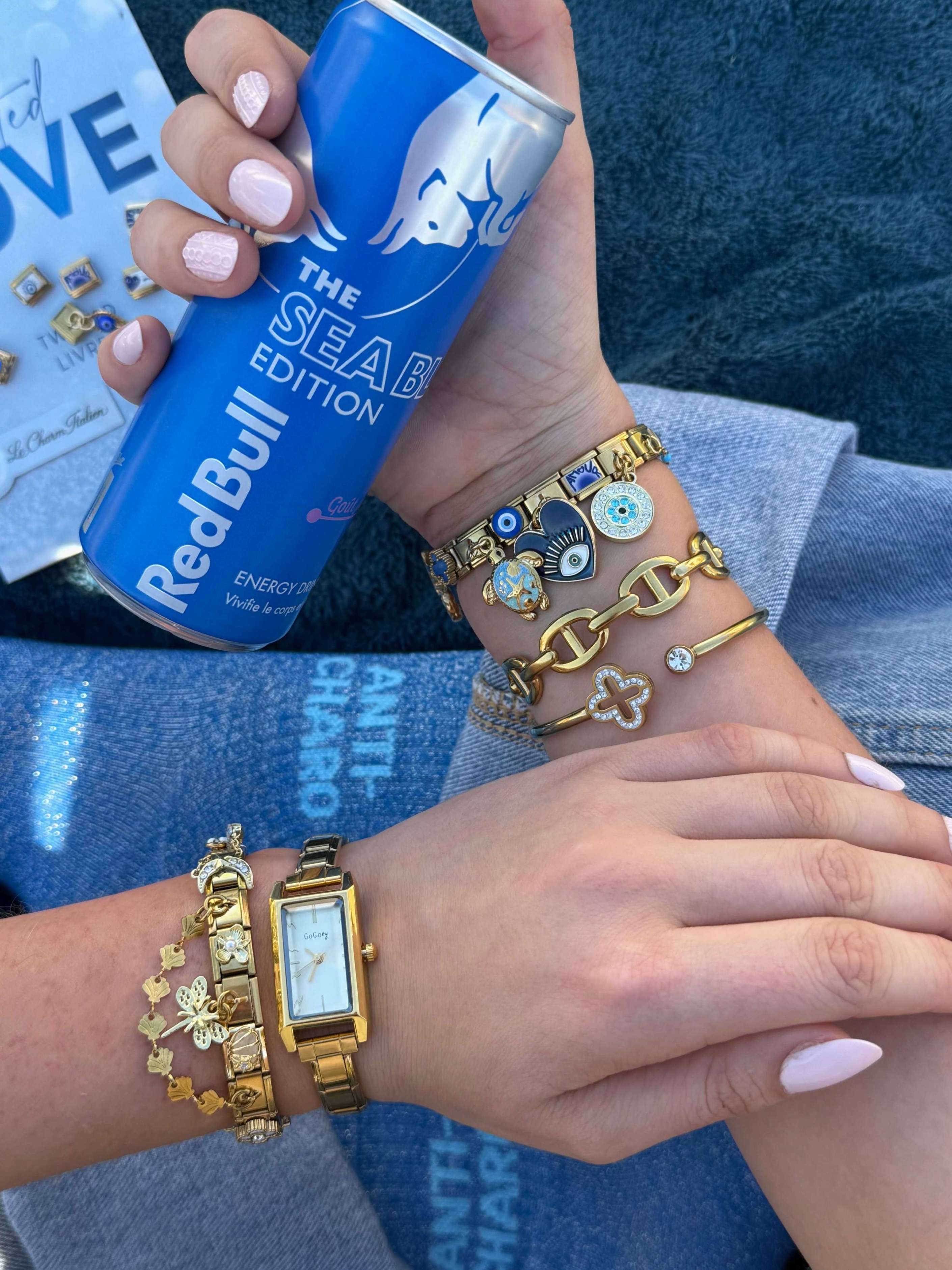 bracelet italien doré avec charms œil bleu, cœur et symboles porté au poignet femme