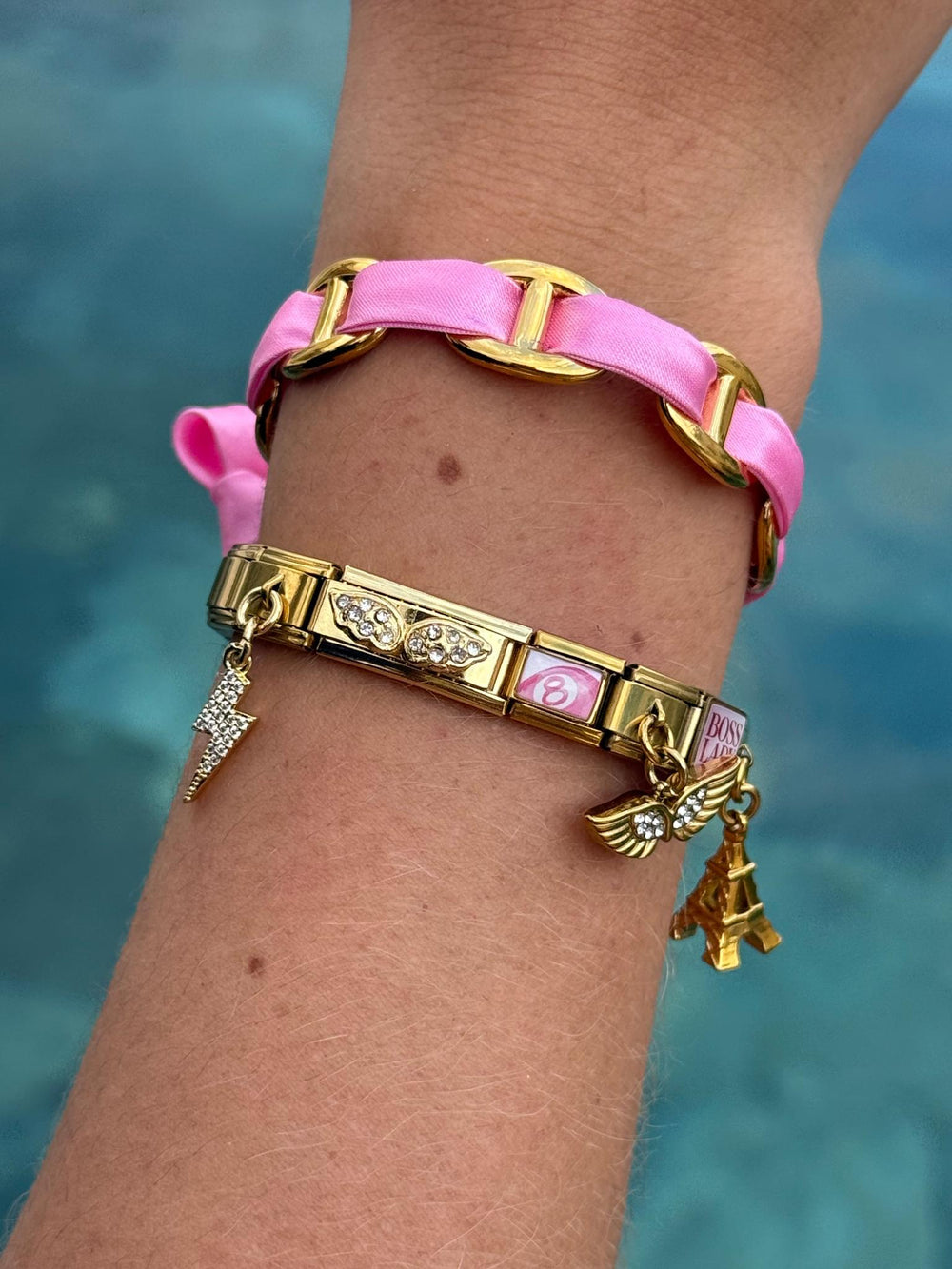 Bracelet Pink Paris porté au poignet, charms ailes strass et Tour Eiffel, acier inoxydable