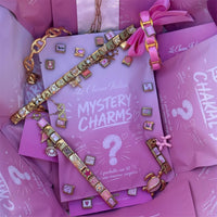 Bracelets charm italien composés de charms roses et dorés en acier inoxydable, posés sur les pochettes Mystery Charms